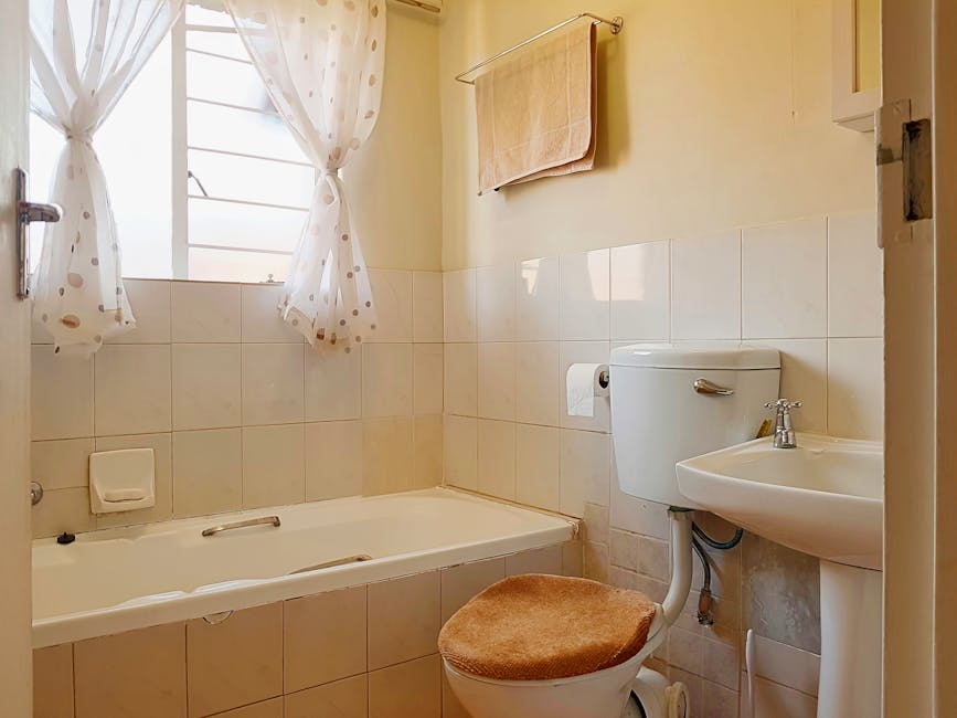 Bright and tidy bathroom featuring a bathtub, toilet, and washbasin with natural light.