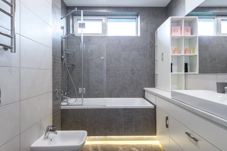Contemporary bathroom featuring sleek gray tiles, bathtub, shower, and vanity.